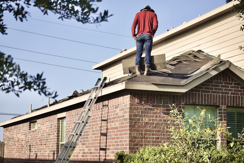 Roofer replacing shingles on a brick home